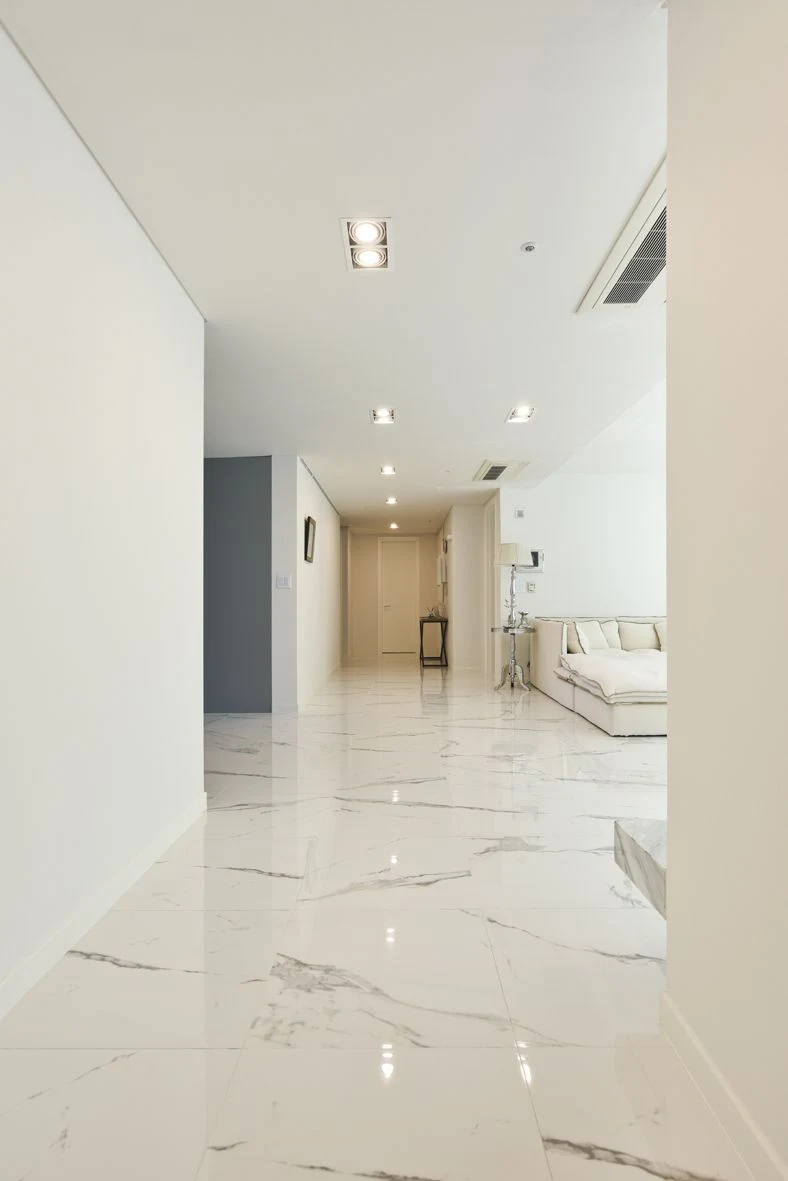 Lantai marmer putih premium di koridor unit apartemen